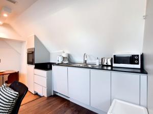 a kitchen with a sink and a microwave at Modern and cozy studio in a former coach house in Robertville