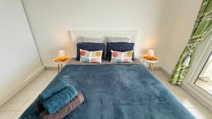 una camera da letto con un letto con coperte blu e cuscini di Appartement de standing vue mer a Schœlcher