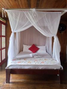 a bed with a canopy with a red pillow on it at Ecohotel Punta Roca in El Valle