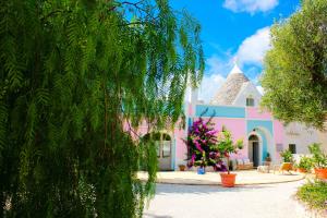 a pink and white house with a turret at Masseria Trullo Sovrano Exclusive B&B in Cisternino