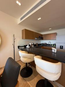 una cocina con encimera negra y sillas blancas en New luxury apartment, en Mérida