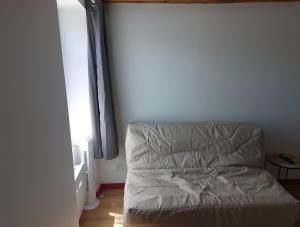an unmade bed in a room with a window at Logements Clos saint Genest 1appartement et 3 studios in Manzat