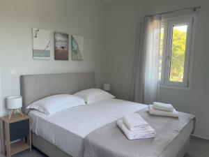 a white bedroom with a bed with towels on it at Villa Eleni Aegina in Egina