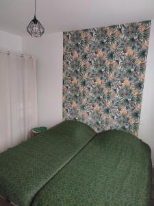 a bed with a green comforter in a bedroom at Les petits gites Ernée in Ernée