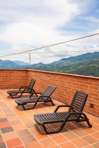 three chairs sitting on a roof with mountains in the background at Hotel Plaza Centro Cocorná in Cocorná +12 photos