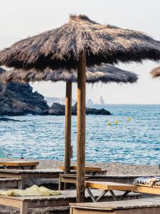 a large straw umbrella on a beach near the water at ONA House Begur in Sa-Riera