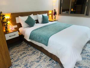 a bedroom with a large white bed with a green blanket at Heart of Dakhla Residence in Dakhla