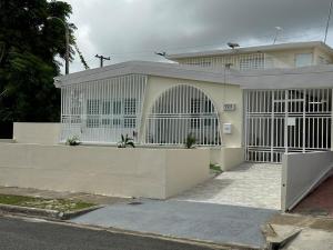 a white house with a gate and a fence at Casa Mi Luz - Family-Friendly 3BR Stay with Parking & Self Check-in in San Juan