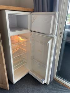 an empty refrigerator with its door open in a room at Tiny house in Uttran, Stockholm in Uttran