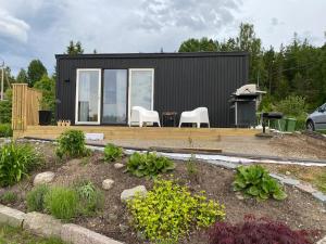 a black tiny house with two white chairs and a table at Tiny house in Uttran, Stockholm in Uttran