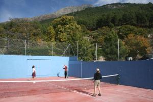 3 personas jugando al tenis en una pista de tenis en Hotel Rural Abejaruco, en Cuevas del Valle