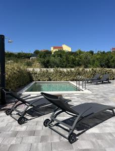 a pair of lounge chairs next to a swimming pool at Villa Santolina in Maslenica