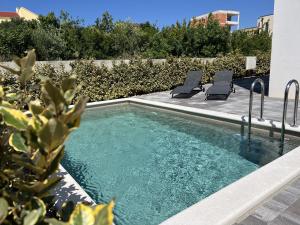 a swimming pool with two lounge chairs next to it at Villa Santolina in Maslenica