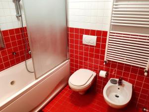 a red tiled bathroom with a toilet and a sink at Happy Guest Apartments - Casa Alpi Orange in Schilpario +7 photos
