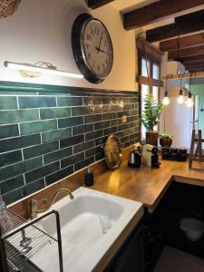 a kitchen with a sink and a clock on the wall at Gîtes à la ferme, Le Jardin Bleu in Tulette