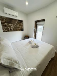 a bedroom with a large white bed with towels on it at Casa das Nogueiras By ALPONTE in Mazedo