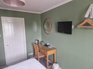 a bedroom with a bed and a desk and a tv at Twenty Seven in Stornoway