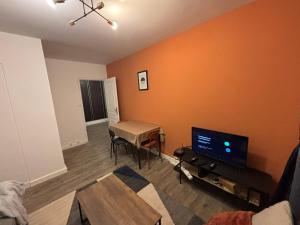a living room with orange walls and a table and a tv at dunes dorees - chambre privee in Rouen