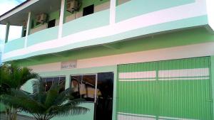 a green and white building with a green garage at Junior Hotel in Anapu