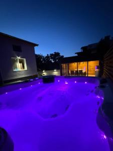 Un jacuzzi morado frente a una casa por la noche. en Вила Mountain Ship, en Dedovo