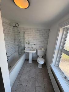 a bathroom with a toilet and a tub and a sink at Spacious 4-Bed Home R&B STAYS Welcomes You in Eastbourne