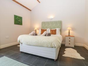 1 dormitorio con 1 cama blanca con 2 lámparas y 1 alfombra en Shepherds Burn Cottage, en Greenhaugh