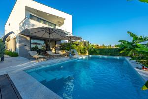 a swimming pool with an umbrella next to a house at Villa Mandarin Paradise with sea view in Pinezici