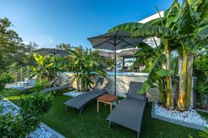 a group of chairs and umbrellas next to a pool at Villa Mandarin Paradise with sea view in Pinezici