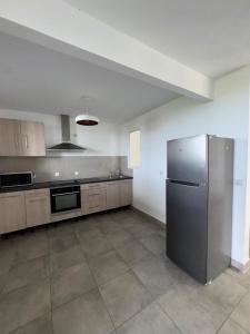 a large kitchen with a stainless steel refrigerator at Appartement élégant avec vue et climatisation in Fort-de-France