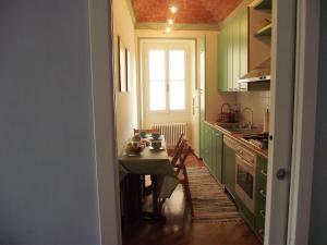 una cucina con armadi verdi, tavolo e finestra di Casa Azzurro Pervinca by Holiday World a Finale Ligure