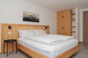una camera da letto con un letto grande con lenzuola bianche di Apartment Il Nocciolo a Livigno