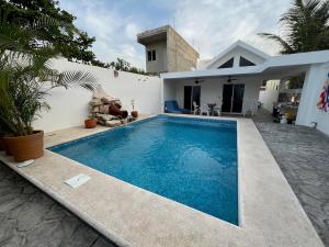 a swimming pool in front of a house at Casa Azul is a tropical oasis in Mahahual