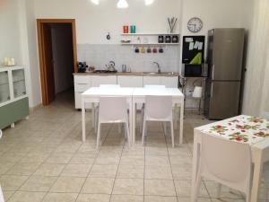 a kitchen with white tables and white chairs and a refrigerator at Akron B&B in SantʼAlessio Siculo