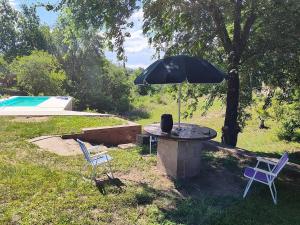 una mesa de piedra con una sombrilla y dos sillas en Cabana Cecilia, en Villa Icho Cruz