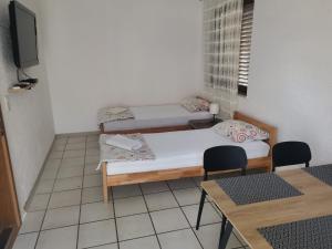 a room with two beds and a table and chairs at Guest House Dijana in Kraljevica