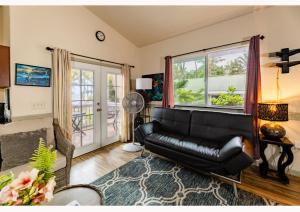 a living room with a black leather couch and a window at The Dolphin Cottage at Kehena Beach in Kehena