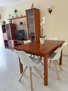 a wooden dining room table with white chairs and a television at Charming Salema in Salema +11 photos