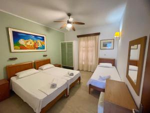a bedroom with two beds and a ceiling fan at Kathrin apartments in Ipsos