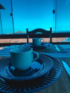 two coffee cups and saucers sitting on a table at Casa Pé na Areia 027 QUARTO CASAL 1 in Guarapari