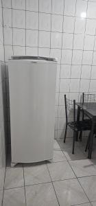 a white refrigerator in a room next to a table at Apartamento temporada 2 quartos em Vila Velha in Vila Velha