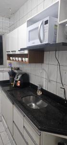 a kitchen counter with a sink and a microwave at Apartamento temporada 2 quartos em Vila Velha in Vila Velha +1 photo
