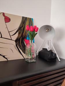 a glass vase with flowers on a table with a painting at Casa da Olívia in Castelo Branco