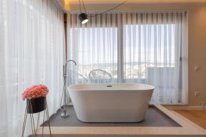 a bathroom with a white tub in front of a window at Prishtina City Apartments 2 in Pristina +84 photos