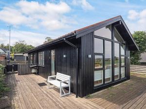 a black house with a white bench on a deck at 4 person holiday home in Sæby-By Traum in Sæby