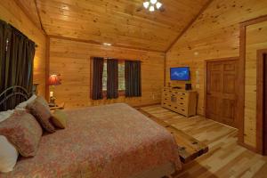 a bedroom with a bed and a television in a log cabin at Sweet Tranquility Pool Lodge in Cosby +31 photos