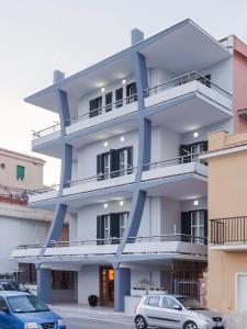 un edificio blanco y azul con coches aparcados delante en Hotel Riviera, en Anzio