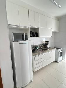 a kitchen with white cabinets and a white refrigerator at Apê Master 3 dorm espaçoso in São Carlos
