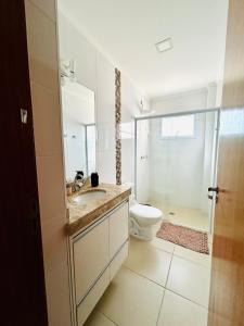 a white bathroom with a toilet and a sink at Apê Master 3 dorm espaçoso in São Carlos