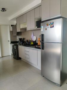 a stainless steel refrigerator in a kitchen with white cabinets at Quarto privativo Morumbi in São Paulo