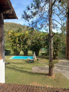 a tree and a chair next to a swimming pool at Casa da Serra - Teresópolis in Teresópolis